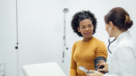 Doctor checking woman patient's blood pressure